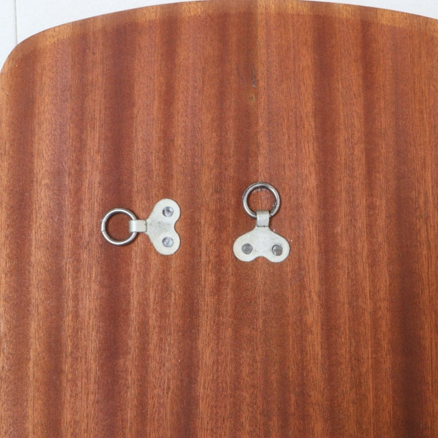 Close-up of vintage mid-century teak wall mirror back showing warm wood grain and two metal hanging hooks.