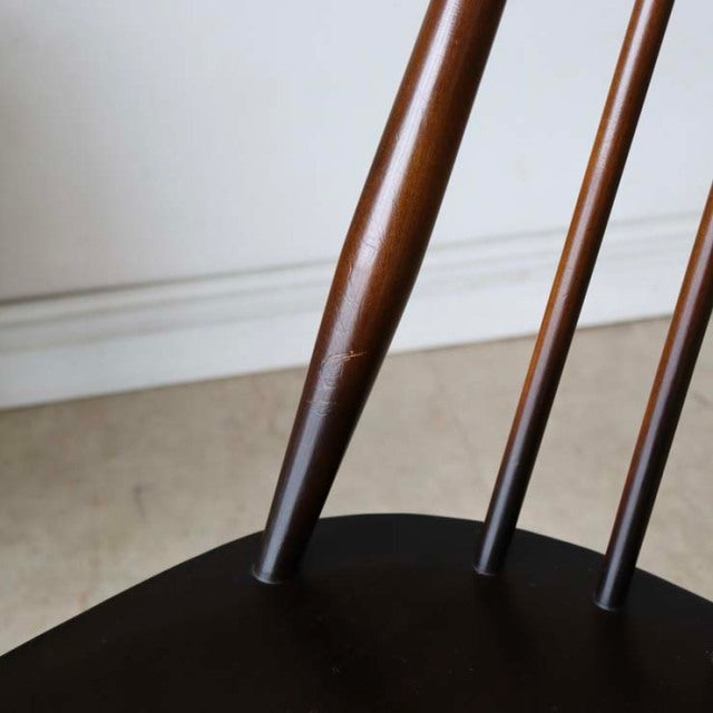 Close-up of vintage British mid-century Ercol Goldsmith dining chair backrest with teak spindles and dark stained wooden.
