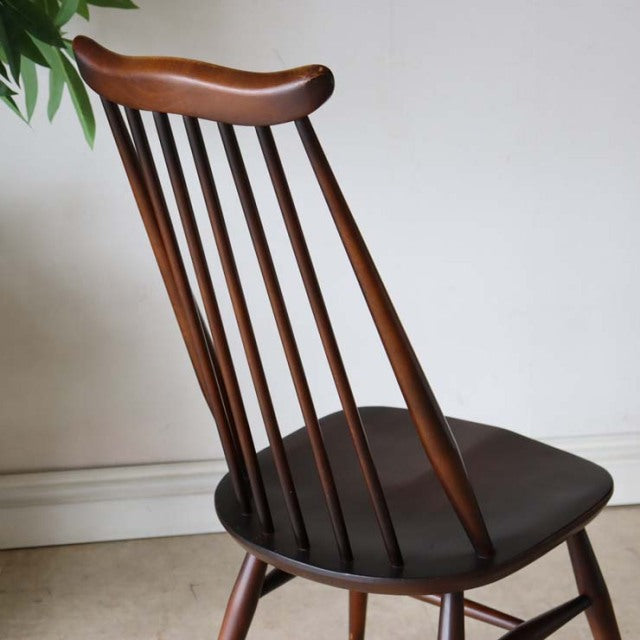 Vintage British mid-century dining chair with teak wood spindle back and dark leather seat.