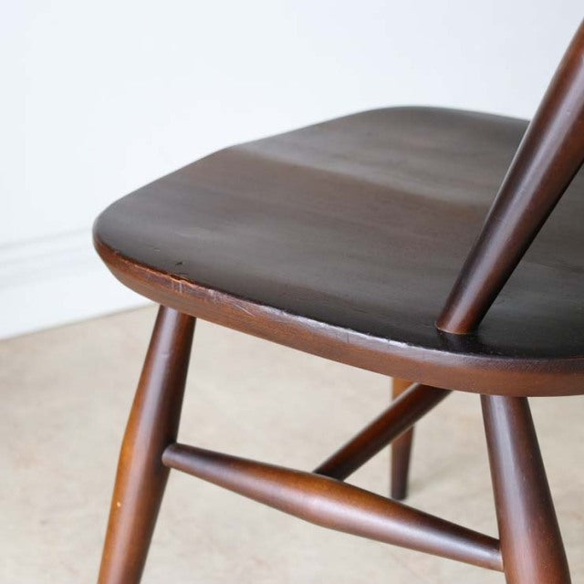 Vintage British mid-century teak dining chair seat and turned legs with smooth wood grain finish.