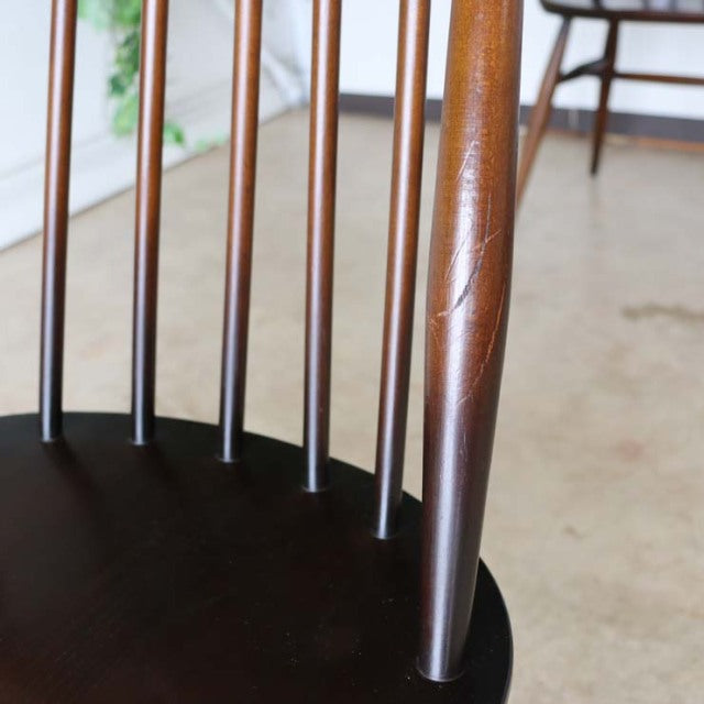 Vintage British mid-century dining chair with teak wood grain, slender spindled backrest, and tapered legs.