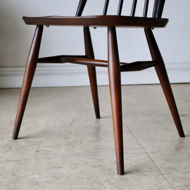 Vintage British mid-century teak dining chair with tapered legs and visible wood grain.