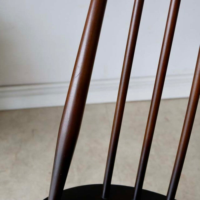 Close-up of vintage British mid-century teak dining chair legs and slender spindle backrest showing smooth wood grain and.