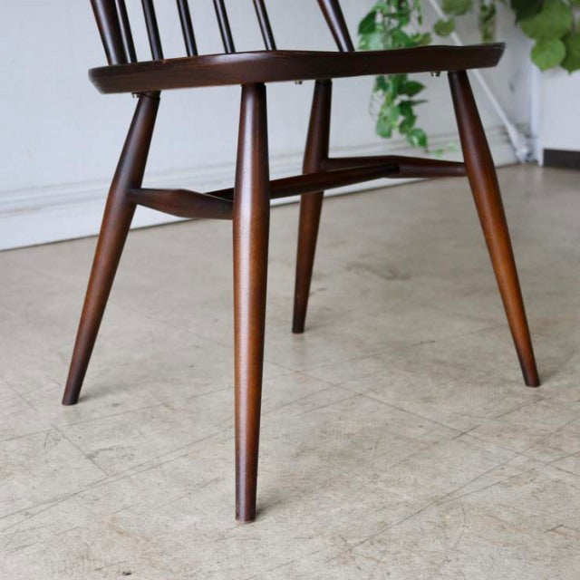 Mid-century British vintage Ercol Goldsmith dining chair in teak with smooth wood grain and tapered legs visible against a.