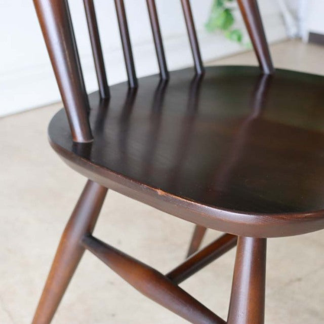 Vintage British mid-century teak dining chair with spindle back and tapered legs showing rich wood grain.