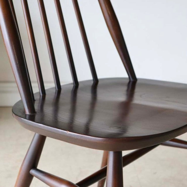 Vintage British mid-century teak dining chair by Ercol with smooth grain, elegant spindle back, and tapered legs.