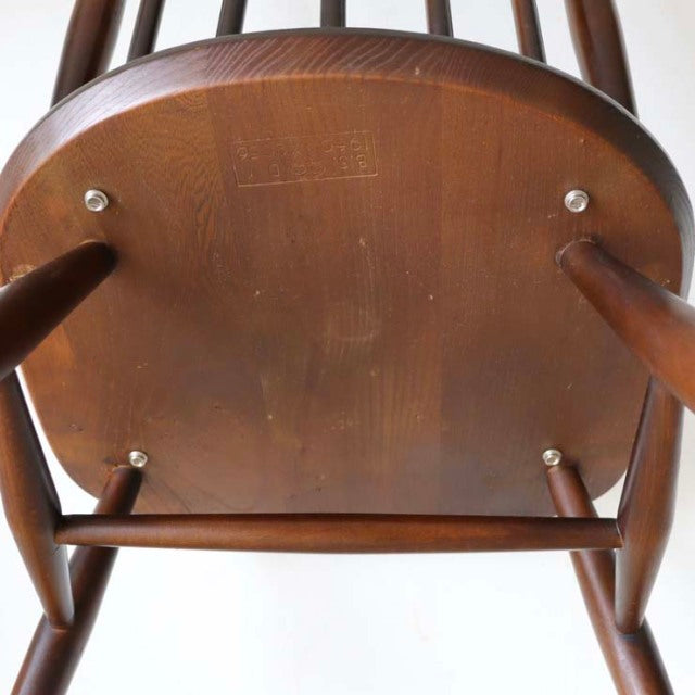 Vintage teak British mid-century dining chair seat underside showing wood grain, spindle legs, and crossbar structure.