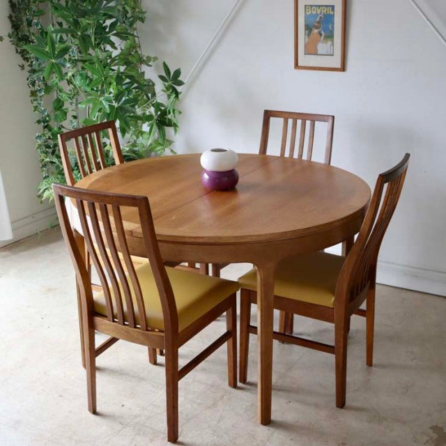 Vintage mid-century teak round dining table by Nathan with sleek wood grain top and four straight legs, paired with matching .
