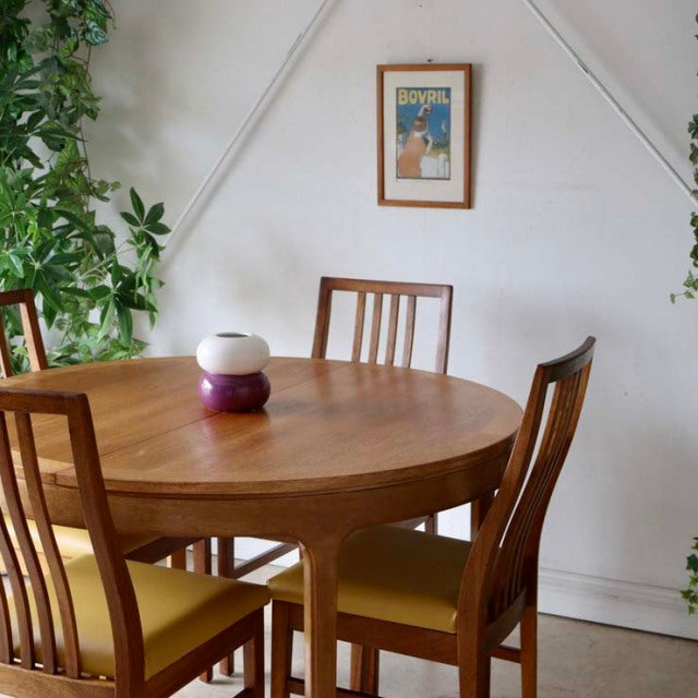 Vintage teak round dining table with British mid-century design, tapered legs, and rich wood grain.