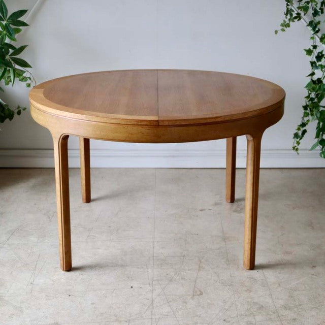 Vintage Nathan round teak dining table with smooth wood grain and tapered mid-century British legs.