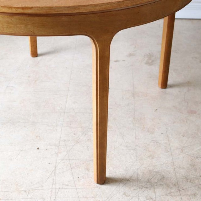Vintage teak round dining table leg detail showcasing smooth wood grain and mid-century British-Denmark design.