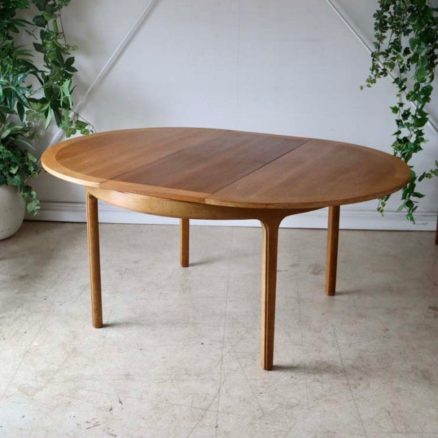 Nathan vintage teak round dining table with tapered legs, mid-century British design from Denmark, smooth wood grain surface.