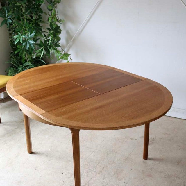 Vintage teak Nathan mid-century dining table with rounded edges, smooth wood grain, and slender tapered legs,.