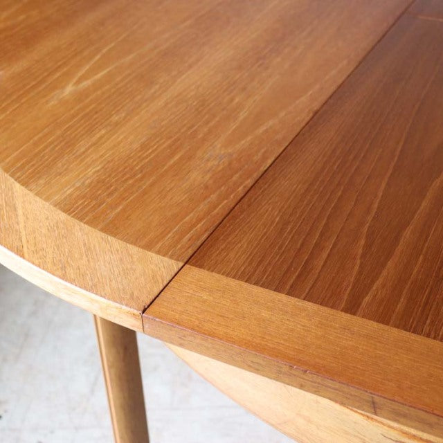 Vintage teak round mid-century dining table with smooth wood grain and tapered British Denmark-style legs.