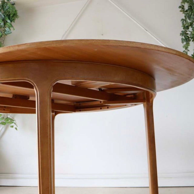 Vintage mid-century teak round dining table by Nathan with smooth wood grain and slender tapered legs from British Denmark.