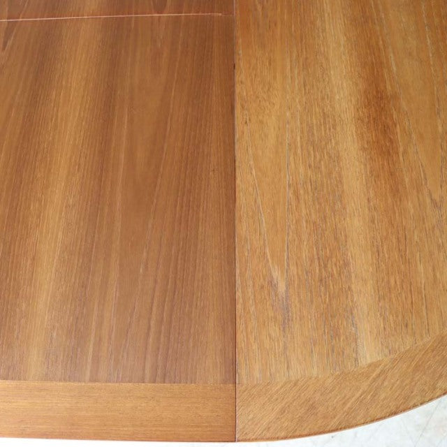 Close-up of vintage teak round dining table top showing rich wood grain and smooth finish, British mid-century style by.