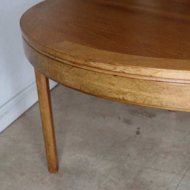 Round vintage teak dining table with smooth grain, tapered legs, mid-century British Denmark design.