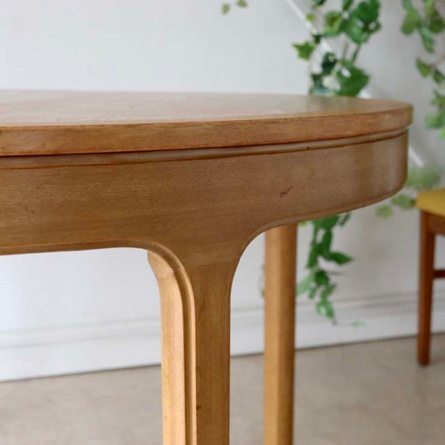 Vintage teak Nathan round dining table with smooth wood grain, mid-century British design, and slender tapered legs from.