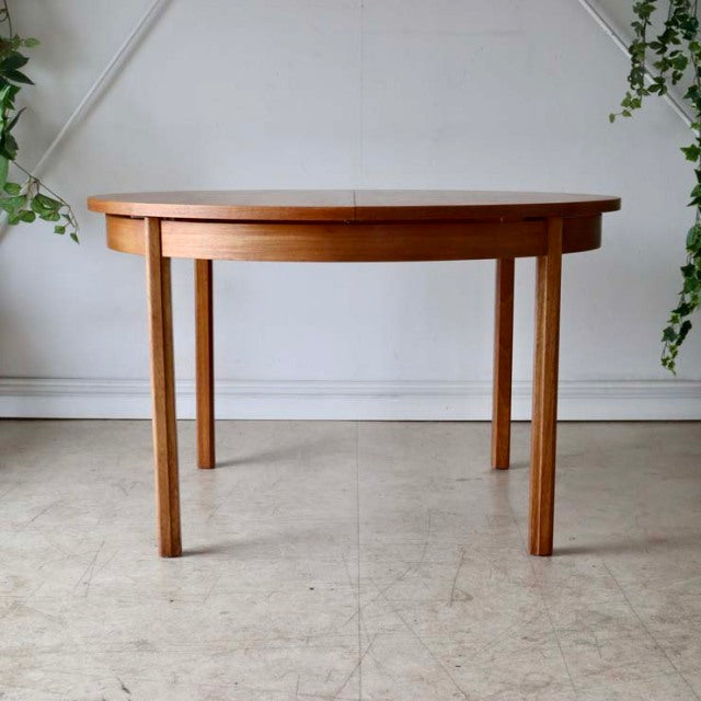 Vintage British mid-century Alfred Cox round dining table in warm teak with smooth grain and tapered legs from Denmark.