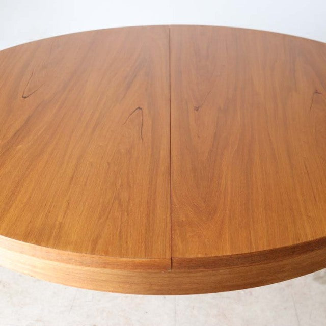 Round vintage teak dining table by Alfred Cox with smooth wood grain and mid-century British design.