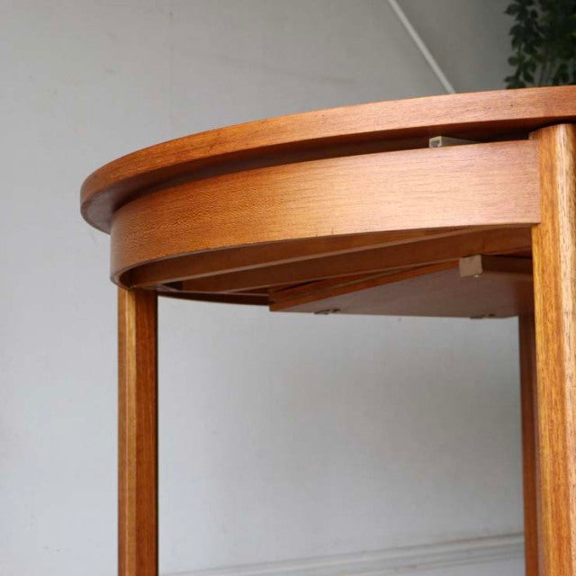 Vintage mid-century British Alfred Cox round dining table in teak with smooth grain and slender tapered legs from Denmark.