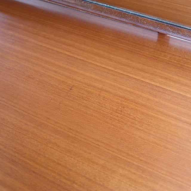 Close-up of vintage mid-century British teak dresser surface showing smooth wood grain and warm honey tones.
