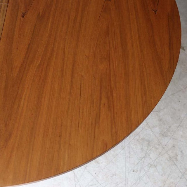 Vintage Alfred Cox mid-century round teak dining table with smooth wood grain and rounded edges.