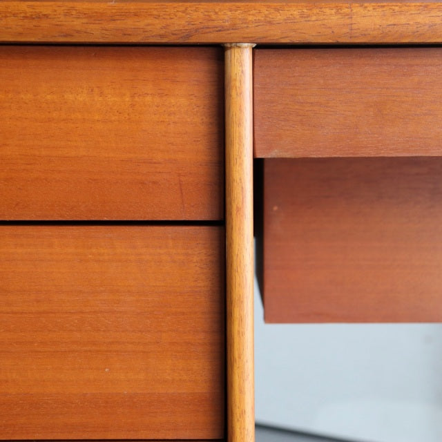 Close-up of vintage mid-century teak dresser drawer with smooth wood grain and slim vertical leg detail, British-Danish style.