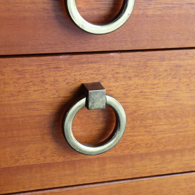 Close-up of vintage British mid-century teak dresser drawer showing smooth wood grain and circular metal ring pull handles.