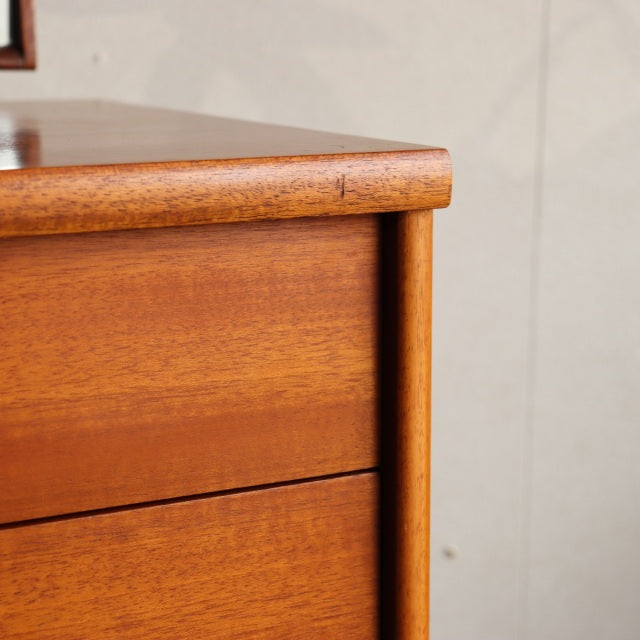 Mid-century British vintage teak dresser corner with smooth rounded edges and visible wood grain.