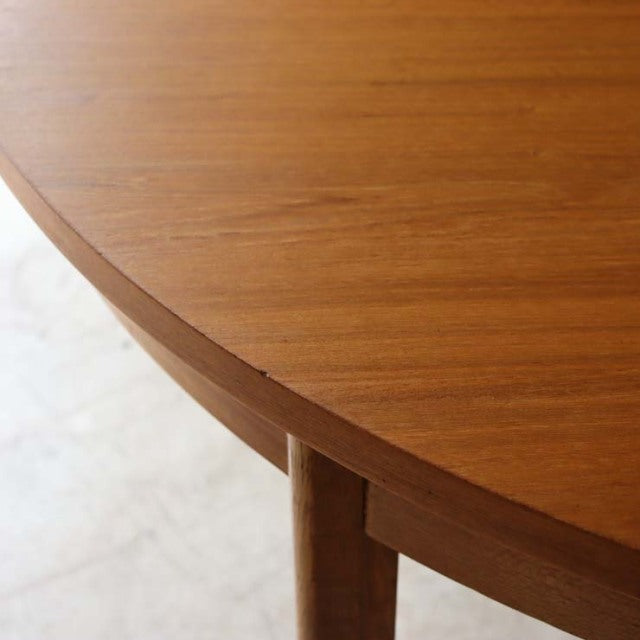Round vintage teak dining table by Alfred Cox with smooth wood grain and tapered mid-century British legs.