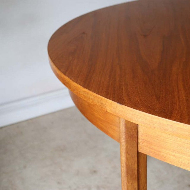 Vintage British mid-century Alfred Cox round dining table in teak with smooth wood grain and slender angled legs from Denmark.