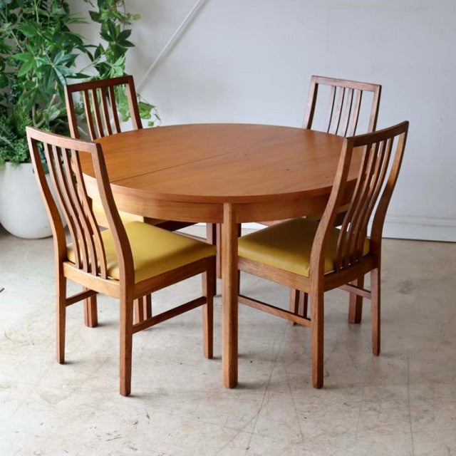 Vintage British mid-century Alfred Cox round teak dining table with four teak chairs featuring vertical slat backs and.