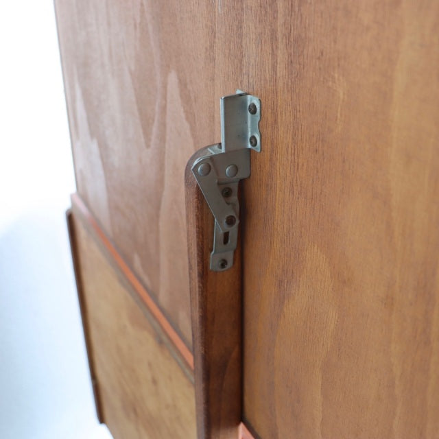 Close-up of vintage mid-century teak wood dresser corner with visible wood grain and metal hinge, British-Denmark design.