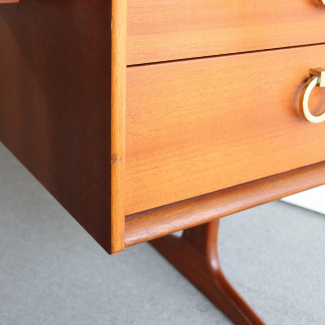 Mid-century British teak dresser corner with smooth wood grain and rounded edges on Danish-style tapered legs.