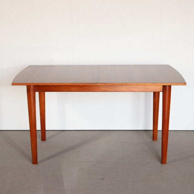 Vintage mid-century British teak dining table with smooth wood grain, rectangular top, and tapered legs from Denmark style.