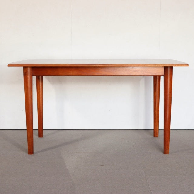 Vintage mid-century teak dining table with clean rectangular top and tapered British-style legs, showcasing warm wood grain.
