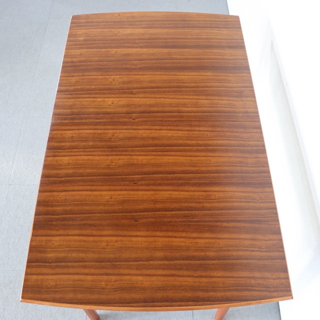 Rectangular vintage teak dining table with smooth wood grain, mid-century British-Denmark design, slender tapered legs.