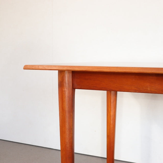 Vintage mid-century British teak dining table with clean lines, rectangular top, and tapered legs showing rich wood grain.