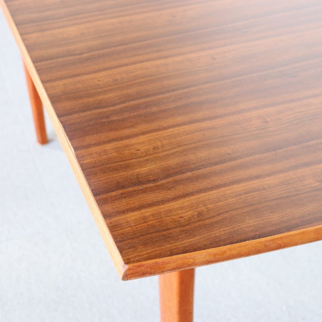 Vintage mid-century teak dining table with rich wood grain and slender tapered legs, British and Danish design influences.