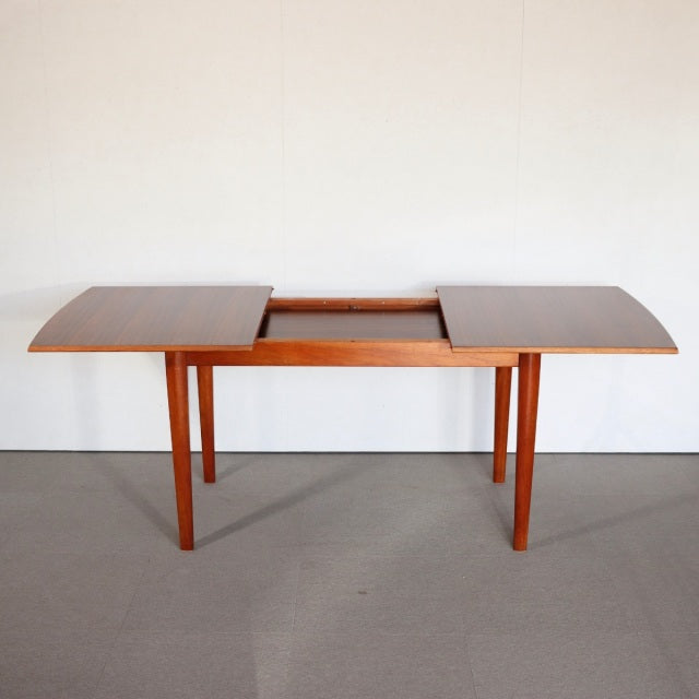 Mid-century British vintage teak dining table with extendable top, rectangular shape, and slender tapered legs.