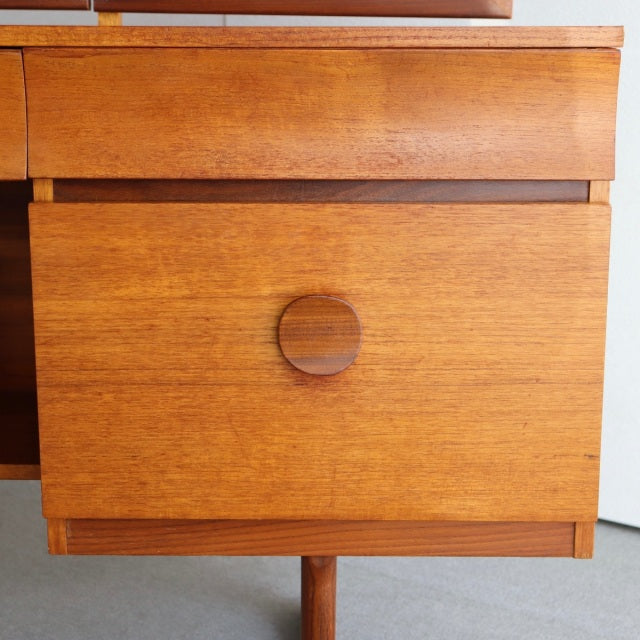 Mid-century British teak dresser drawer with visible wood grain and circular wooden handle.