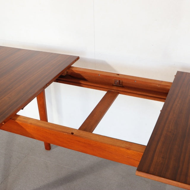 Mid-century British teak dining table with rich wood grain, extending mechanism, and sturdy square legs.