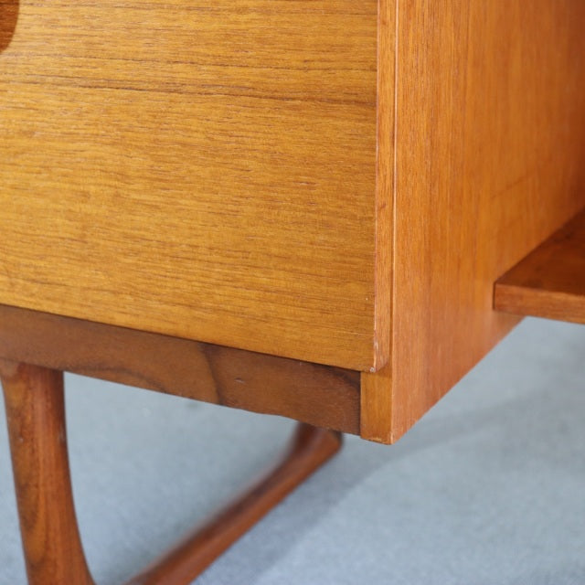 Close-up of vintage teak dresser corner showcasing mid-century British-Denmark style with smooth wood grain and slender.