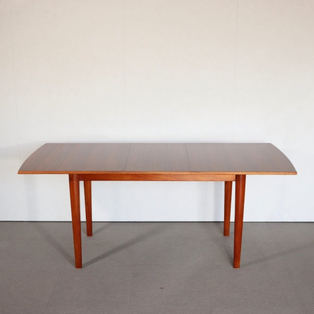 Mid-century British vintage teak dining table with rectangular top and slender tapered legs from Denmark.