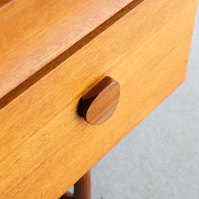 Close-up of vintage British mid-century teak dresser drawer with round wooden handle and visible wood grain.
