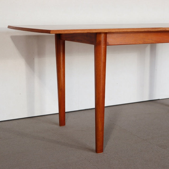 Mid-century British vintage teak dining table with rectangular top and tapered legs, showcasing rich wood grain from Denmark .
