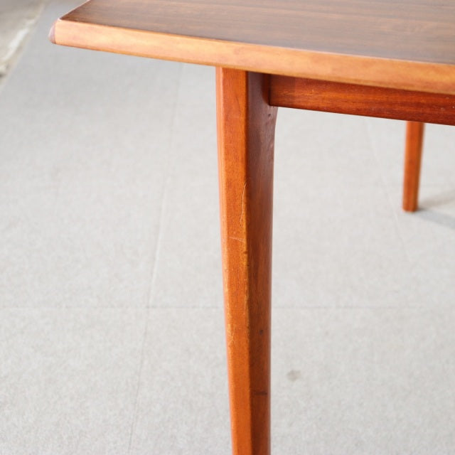 Vintage British mid-century teak dining table corner with tapered legs and rich wood grain detail from Denmark.