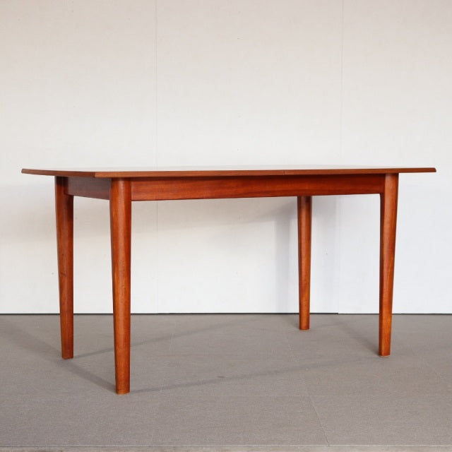 Mid-century British vintage teak dining table with rectangular top and tapered round legs, smooth wood grain finish.