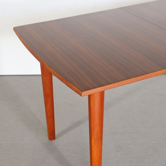 Mid-century British vintage teak dining table with rich wood grain and slender tapered legs from Denmark.
